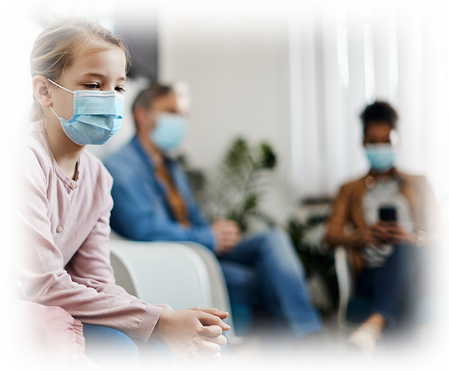 Sick child in waiting room with other patients wearing a face mask